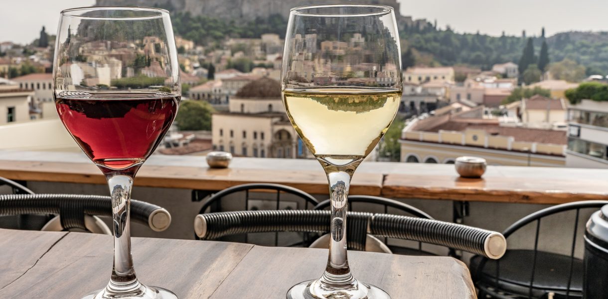 Glasses of wine with a view of the Acropolis in Athens, Greece. Red and white wine. Wide angle close up.